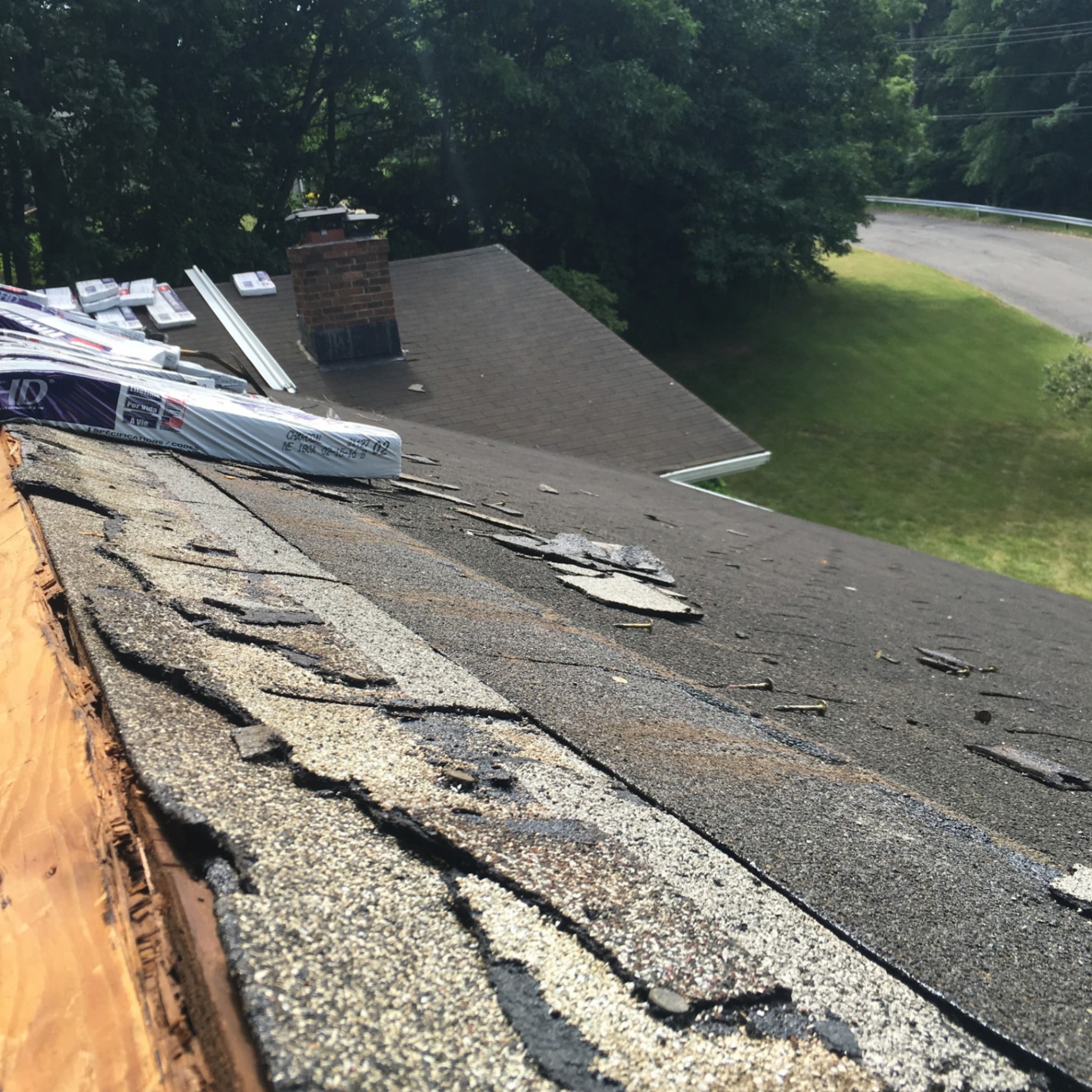 Old curling asphalt shingles on the ridge before tear-off