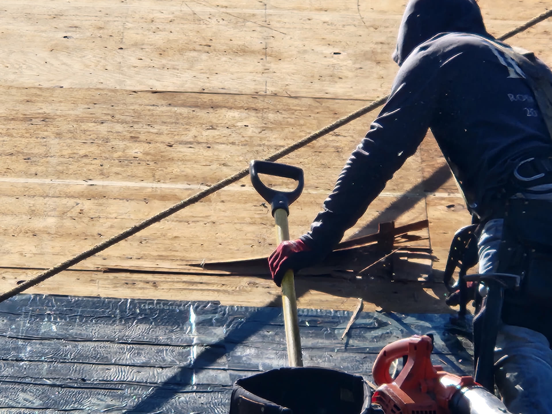 Roofer scraping the deck clean down to bare plywood