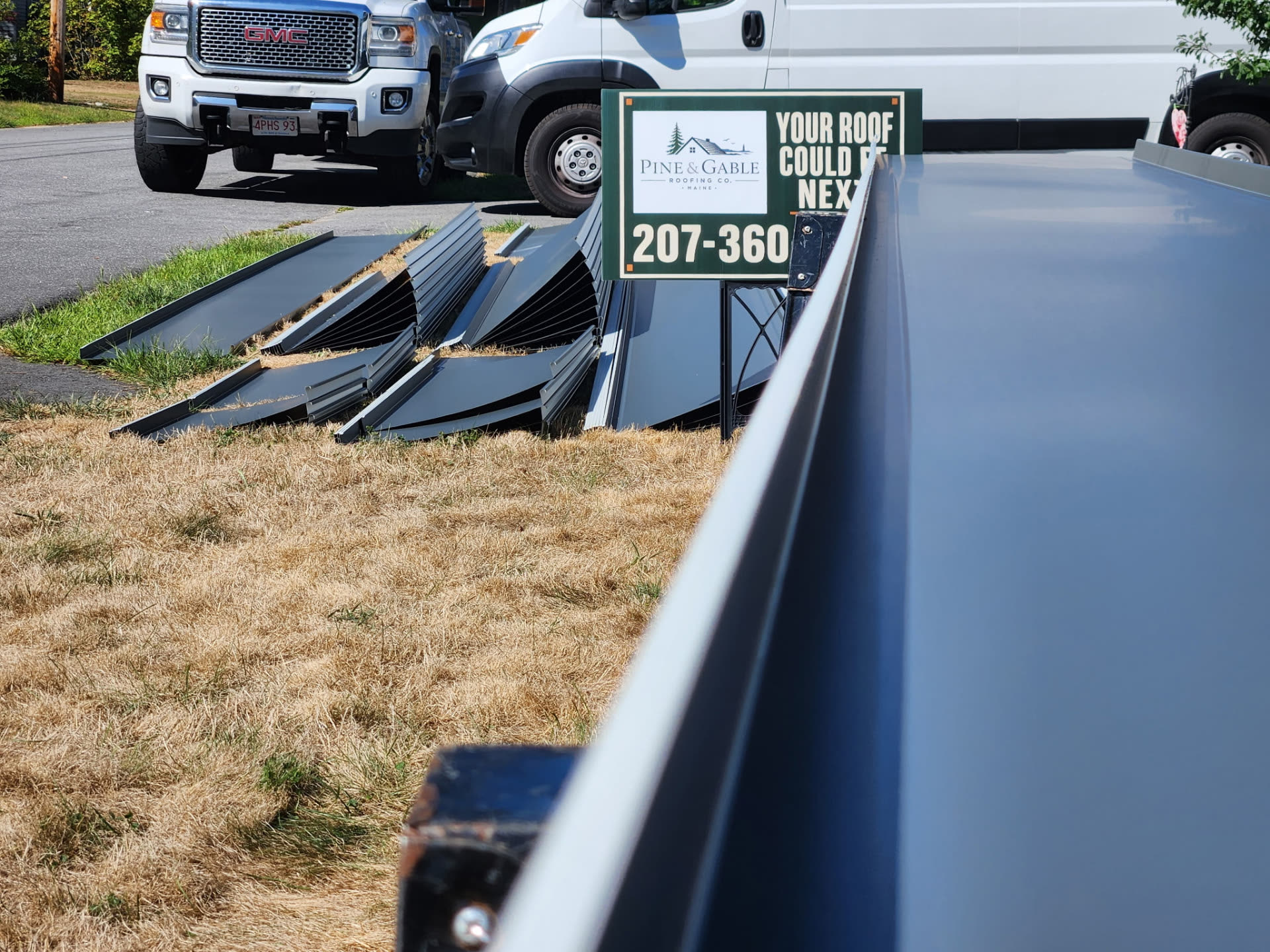 Drexel standing seam metal panels staged on the lawn next to the Pine & Gable job sign