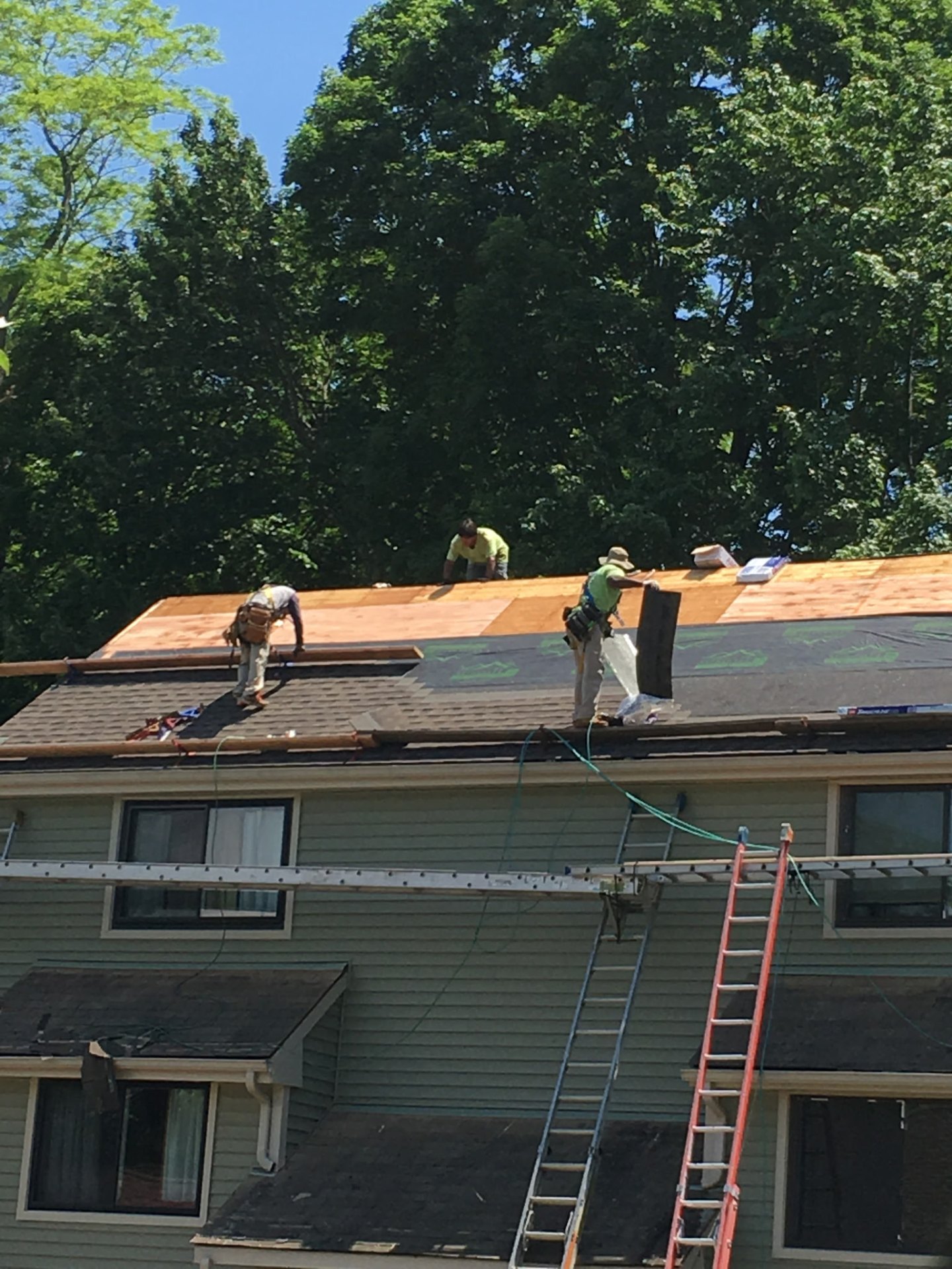 Three-man crew laying synthetic underlayment and starter course