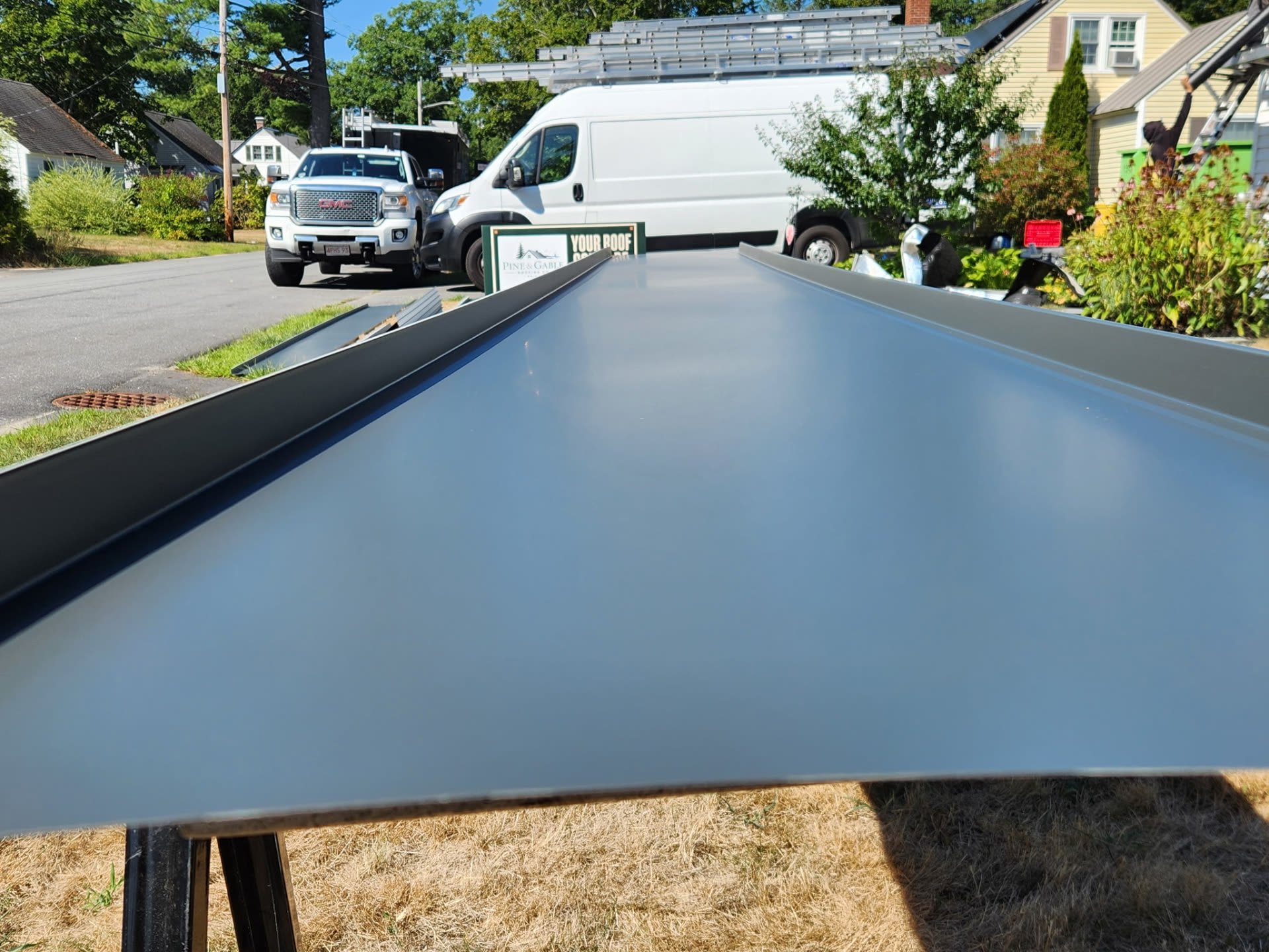 Close-up of a charcoal standing seam metal panel showing the raised seam profile
