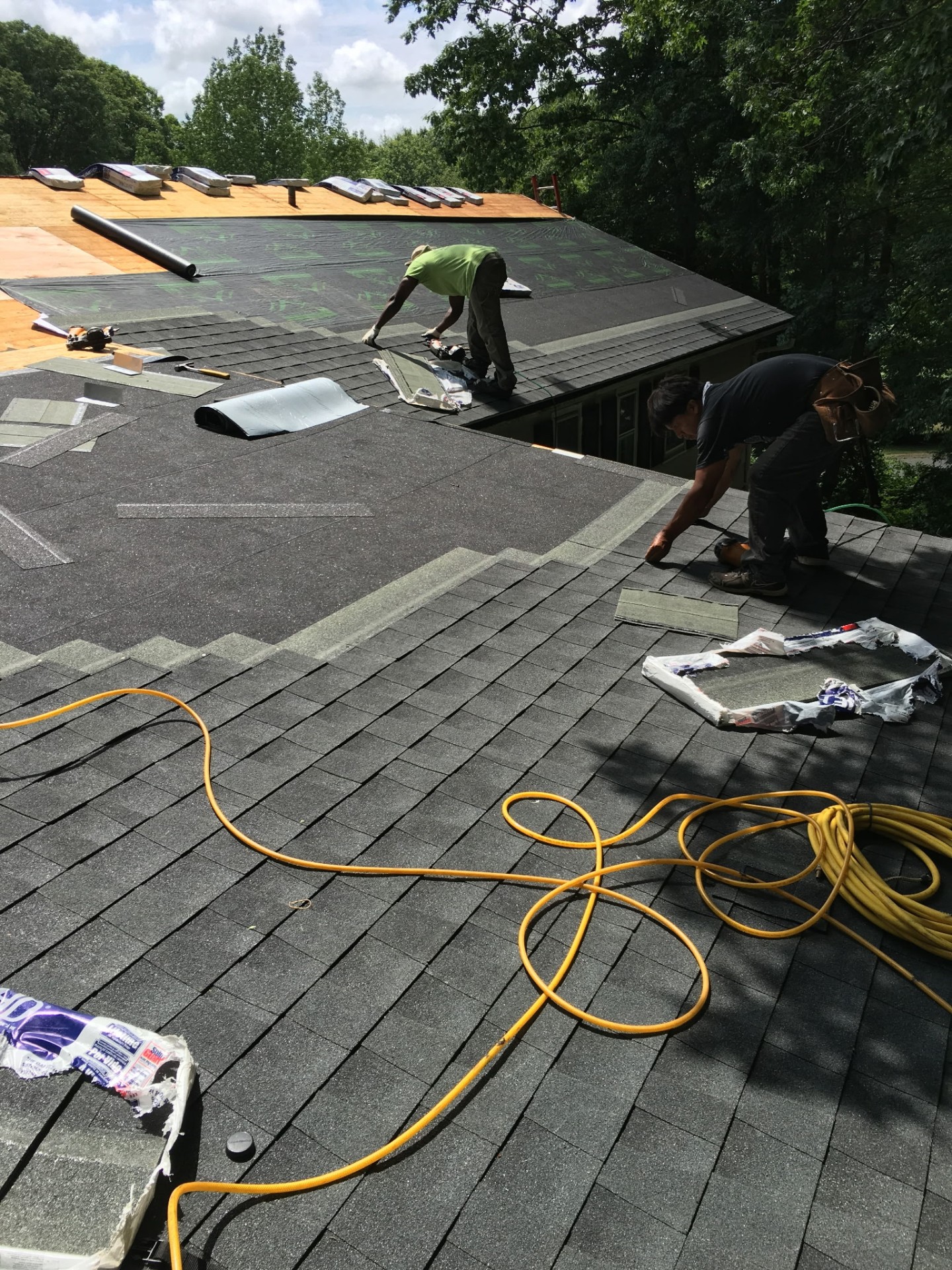 Two roofers finishing the ridge cap on the completed slope
