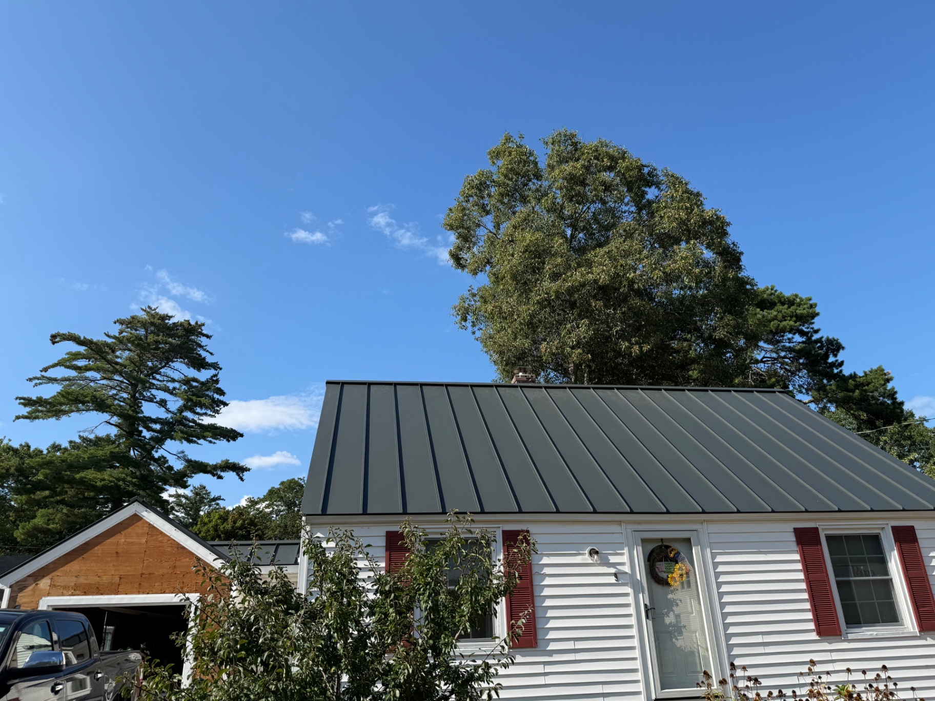 Finished charcoal standing seam metal roof on the front slope of the white Brunswick cape