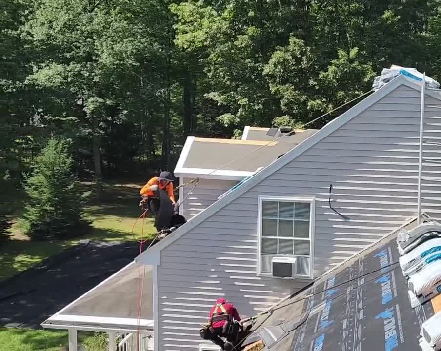 Video of two roofers working the slopes of the Wells home, underlayment on the front slope and tear-off finishing at the rear