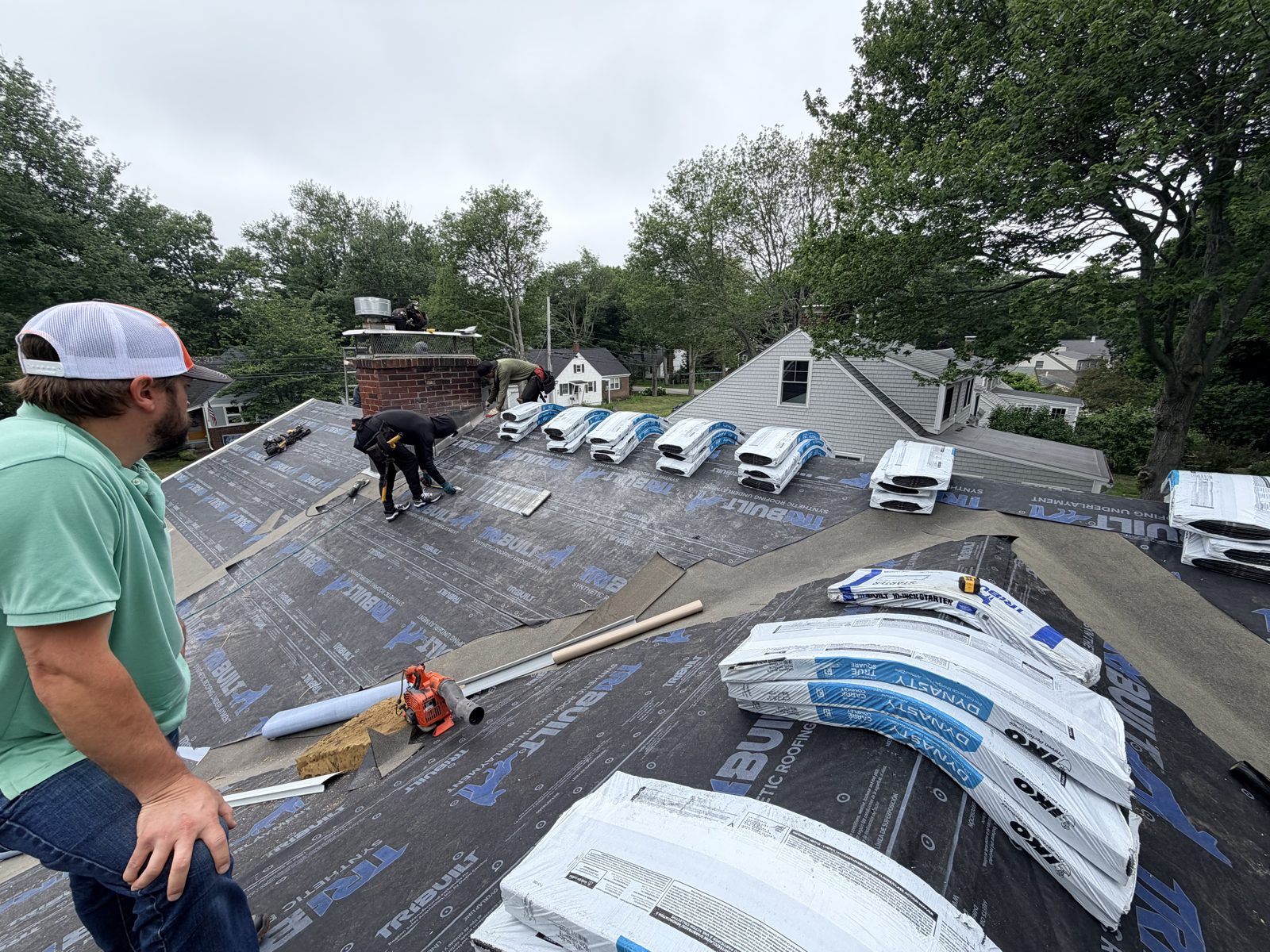 Synthetic underlayment installed with shingle bundles staged across the roof