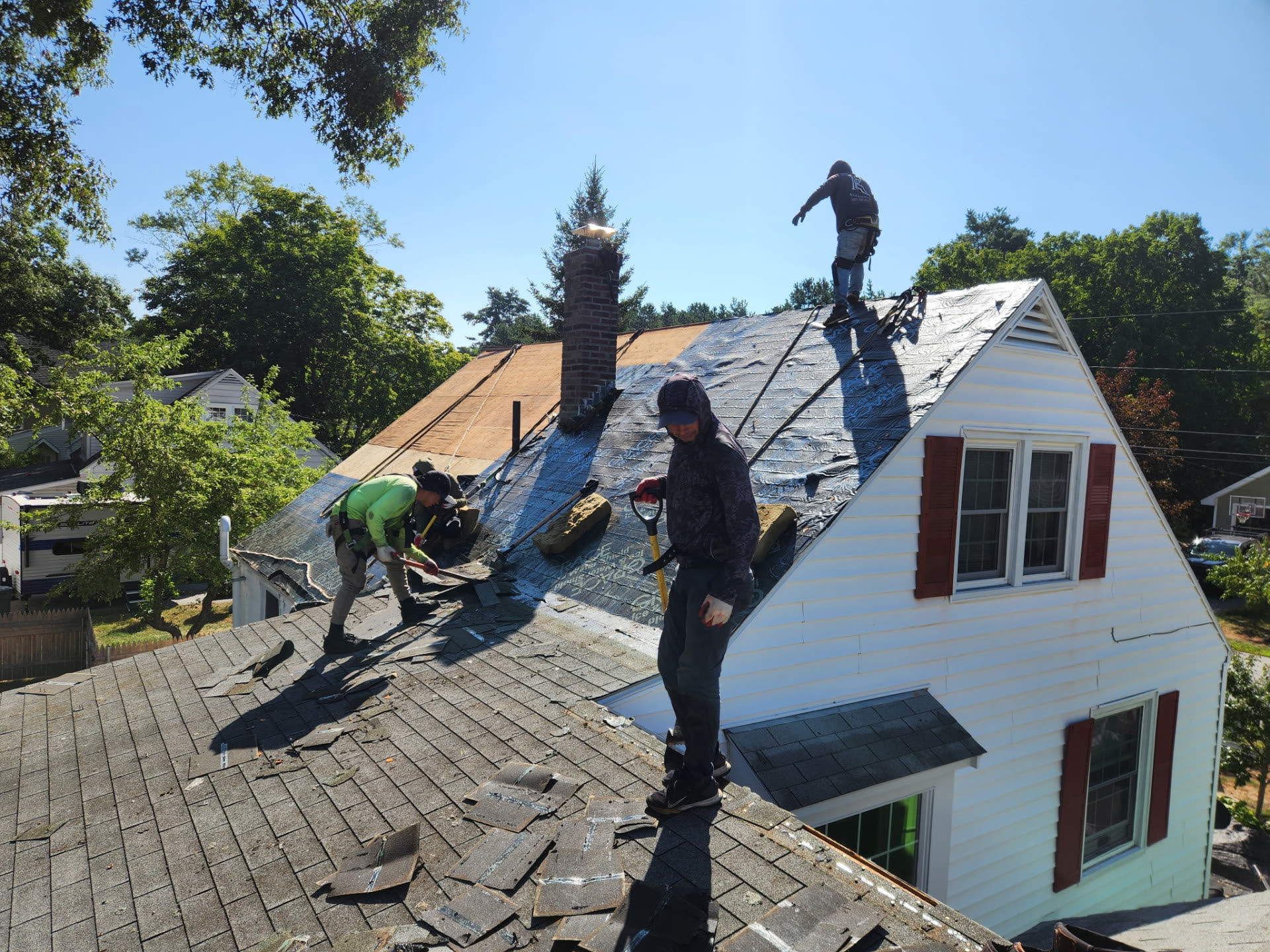 Roofers stripping old shingles around the brick chimney